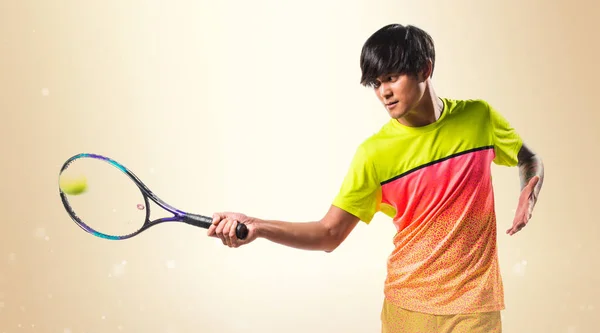 Azjatycka tenis gracz człowieka na tle ochry — Zdjęcie stockowe