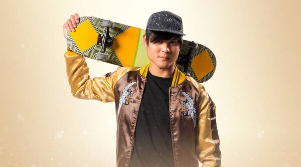 Азиатский городской житель со скейтом на охерном фоне
