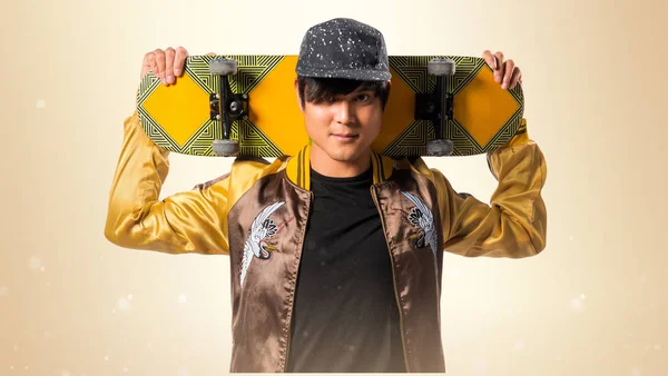 Asiatischer Stadtmensch mit Skate auf ockerfarbenem Hintergrund — Stockfoto