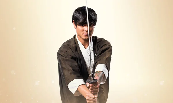 Asijské samuraj muž s katana na okrové pozadí — Stock fotografie