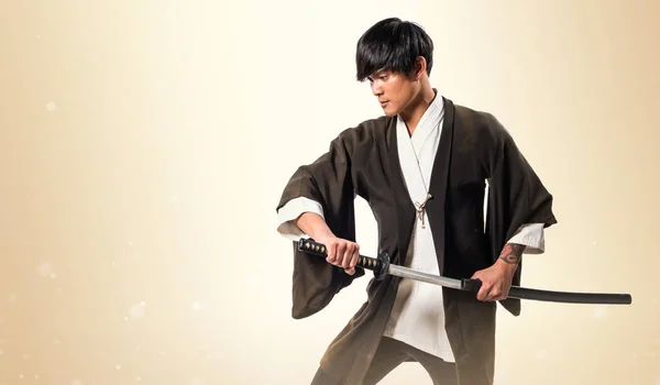 Samurai asiático hombre con katana en ocre fondo — Foto de Stock