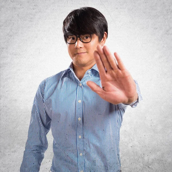 Asiatische schöner Mann mit Brille Herstellung Stoppschild auf strukturierte bac — Stockfoto