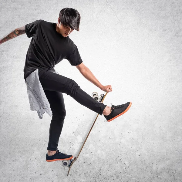 Asiático urbano hombre saltar con skate en texturizado fondo —  Fotos de Stock