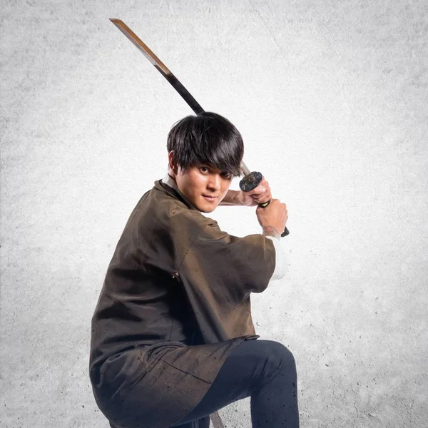 Asiatiska samurai man med katana på texturerat bakgrund — Stockfoto