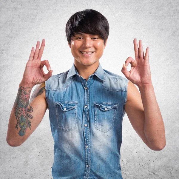 Asiático guapo hombre haciendo OK signo en texturizado fondo — Foto de Stock