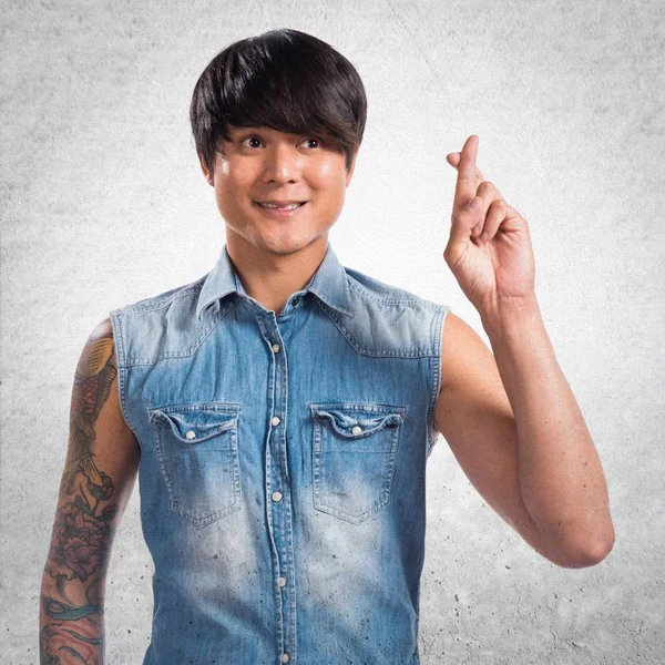 Asiático guapo hombre con su dedos cruce en texturizado backgro — Foto de Stock