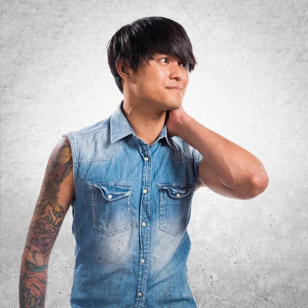 Yakışıklı adamla Asya: boyun ağrısı dokulu arka plan üzerinde