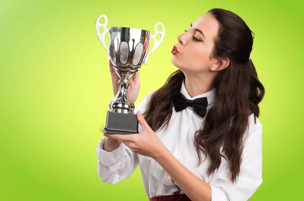 Junge schöne Kellnerin hält eine Trophäe auf buntem Hintergrund — Stockfoto