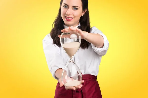 Young beautiful waitress  holding vintage clock on colorful background — Stock Photo, Image