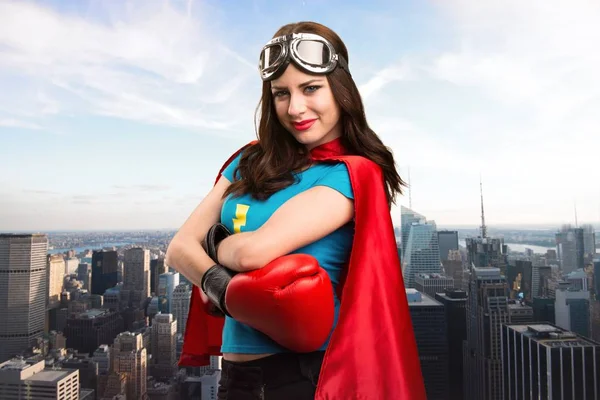 Menina super-herói bonito com luvas de boxe com a cidade no fundo — Fotografia de Stock