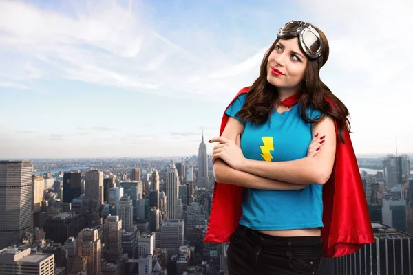 Bastante chica superhéroe mirando hacia arriba con la ciudad en el fondo — Foto de Stock