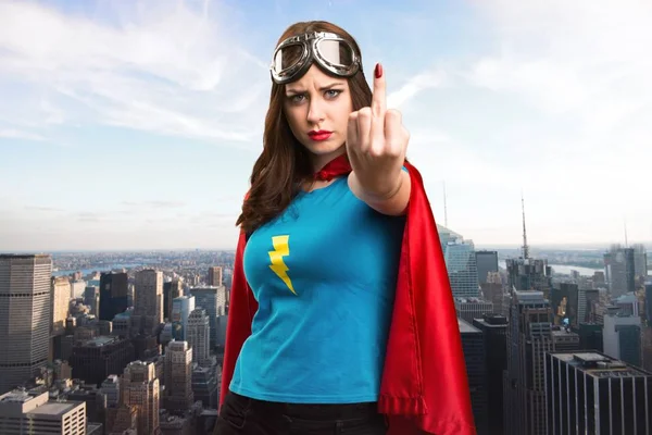 Bastante chica superhéroe haciendo gesto de cuerno con la ciudad en el fondo —  Fotos de Stock