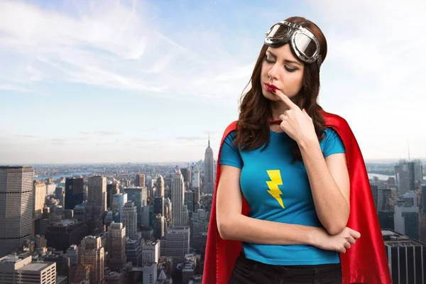 Bastante chica superhéroe pensando con la ciudad en el fondo — Foto de Stock