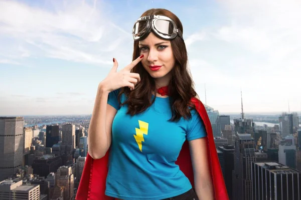 Bastante chica superhéroe mostrando algo con la ciudad en el fondo — Foto de Stock