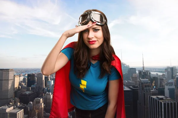 Bastante chica superhéroe mostrando algo con la ciudad en el fondo — Foto de Stock