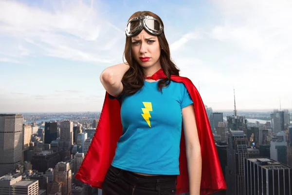 Bastante chica superhéroe con dolor de cuello con la ciudad en el fondo — Foto de Stock