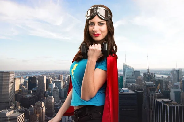 Jolie fille super-héros faisant haltérophilie avec la ville en arrière-plan — Photo
