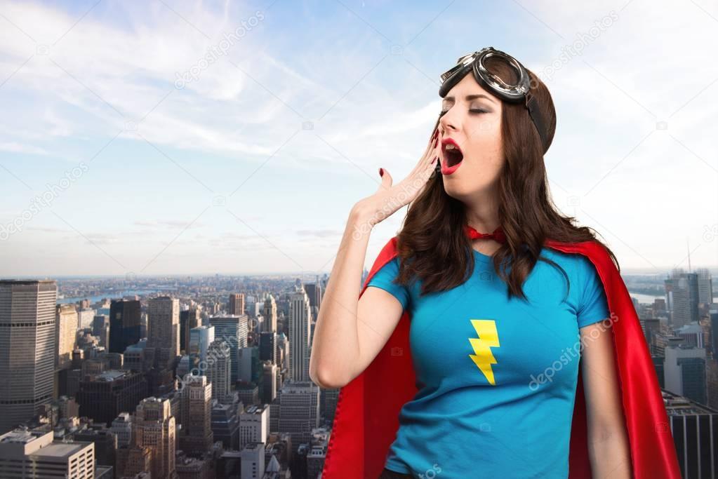 Pretty superhero girl yawning with the city in the background
