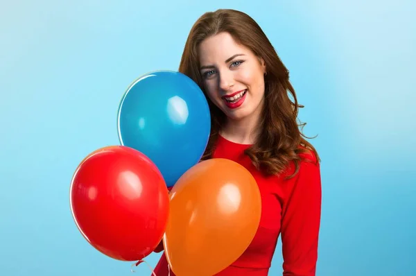 Feliz hermosa joven sosteniendo globos sobre fondo colorido — Foto de Stock