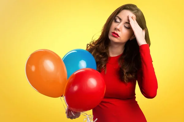 Frustrated beautiful young girl holding balloons and on colorful background — Stock Photo, Image