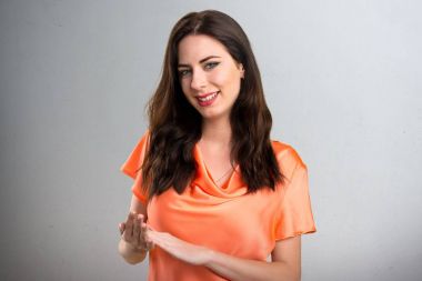 Güzel genç kız gri arka plan üzerinde alkış