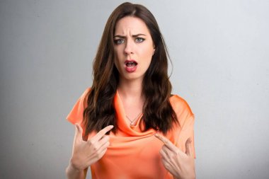 Güzel genç kız yapma sürpriz jest gri arka plan üzerinde