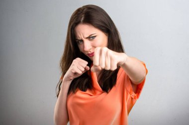 Güzel genç kız gri arka plan üzerinde mücadele