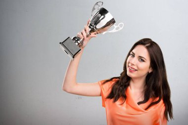 Bir kupa gri arka plan üzerinde tutan güzel genç kız
