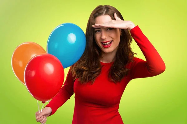 Hermosa joven sosteniendo globos y mostrando algo sobre fondo colorido — Foto de Stock