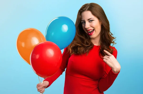 Hermosa joven sosteniendo globos y orgullosa de sí misma sobre un fondo colorido — Foto de Stock
