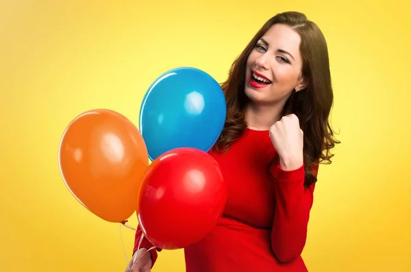Suerte hermosa joven sosteniendo globos sobre fondo colorido — Foto de Stock