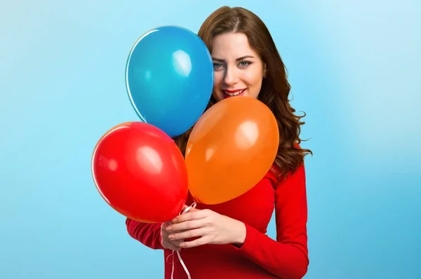 Feliz hermosa joven sosteniendo globos sobre fondo colorido — Foto de Stock