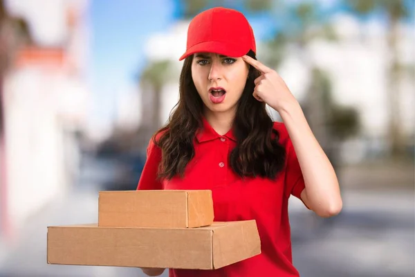 Delivery woman making crazy gesture on unfocused background — Stock Photo, Image