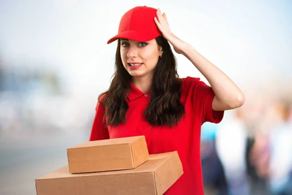 Young delivery woman having doubts on unfocused background — Stock Photo, Image