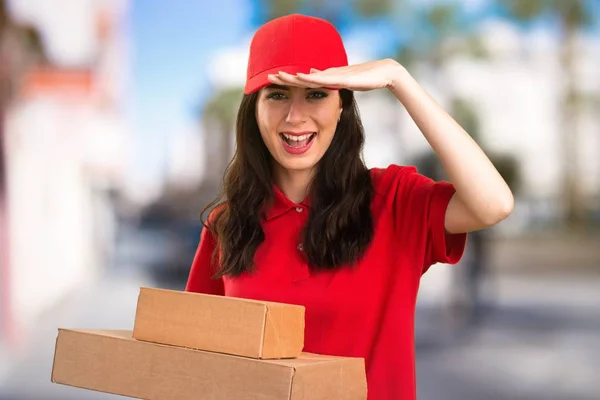 Young delivery woman showing something on unfocused background — Stock Photo, Image