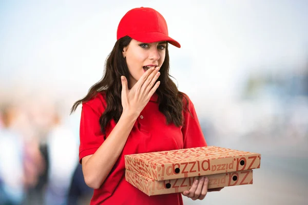 Mulher de entrega de pizza fazendo gesto surpresa em backgr desfocado — Fotografia de Stock