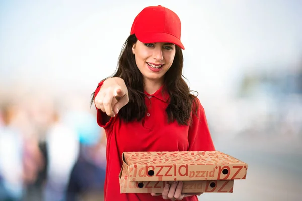 Mulher de entrega de pizza apontando para a frente em backgrou desfocado — Fotografia de Stock