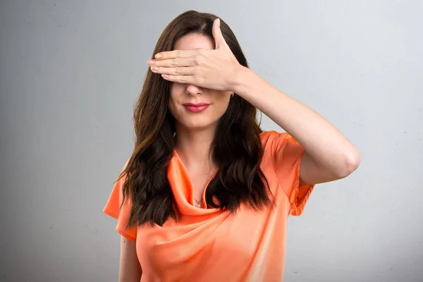 Hermosa joven que cubre sus ojos sobre fondo gris —  Fotos de Stock