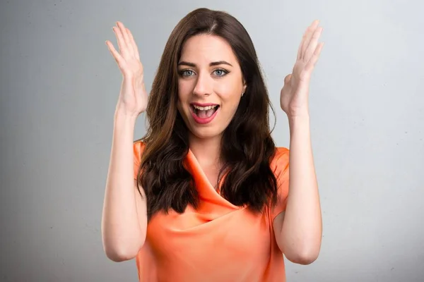 Beautiful young girl making surprise gesture on grey background — Stock Photo, Image