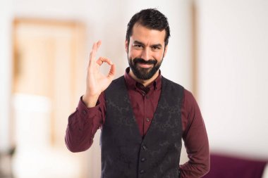 Ok işareti yapma yelek giyen adam 