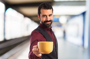 Bir fincan kahve tutan yelek giyen adam 