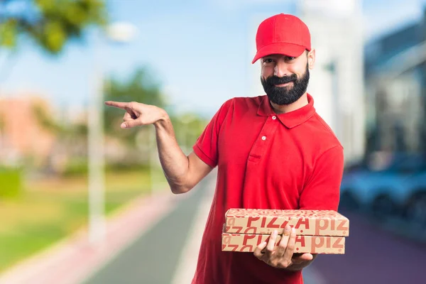 Rozvoz pizzy muž ukázal na bočních — Stock fotografie
