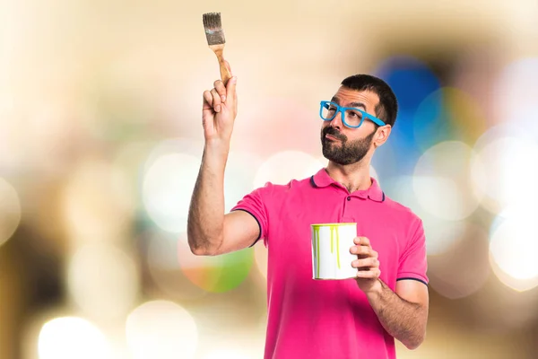 Hombre con ropa colorida sosteniendo una olla de pintura — Foto de Stock