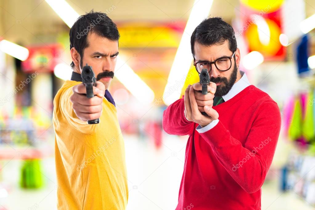 Twin brothers shooting with a pistol 