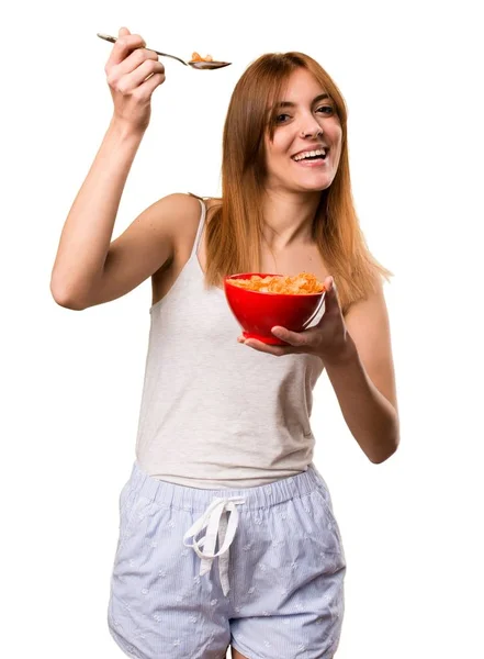 Beautiful girl in pajamas eating cereals from a bowl — Stock Photo, Image