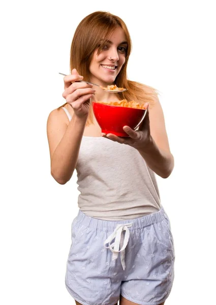 Beautiful girl in pajamas eating cereals from a bowl — Stock Photo, Image