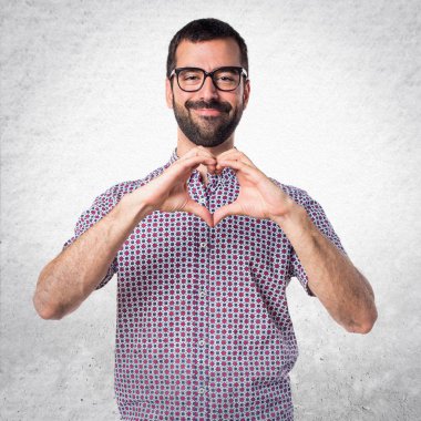 Elleri ile bir kalp yapma gözlüklü adam