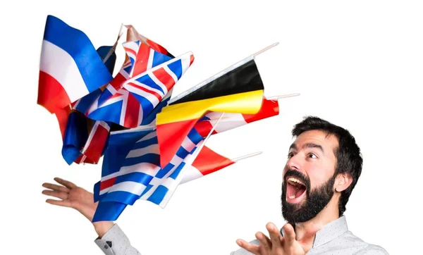 Счастливый красивый мужчина с бородой держит много флагов — стоковое фото