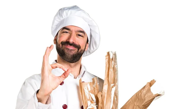 Joven panadero sosteniendo un poco de pan y haciendo señal OK — Foto de Stock