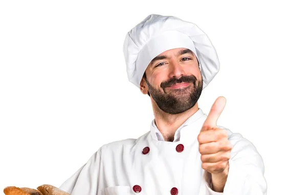 Joven panadero sosteniendo un poco de pan y con el pulgar hacia arriba — Foto de Stock